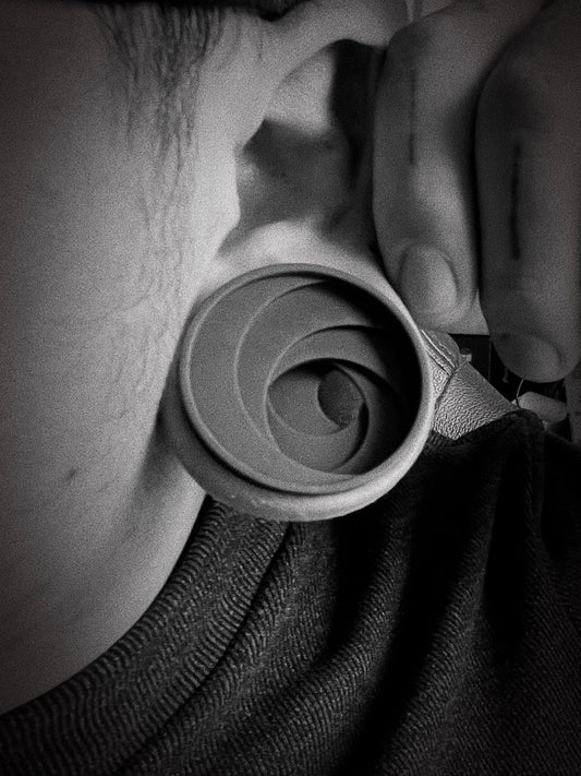 Black and white side profile of a model wearing a gray Swirl double flared ear tunnel