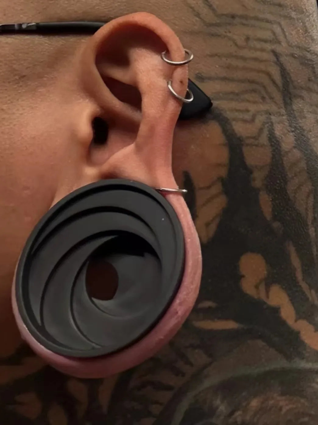 Color side profile of a model wearing a black Swirl double flared ear tunnel