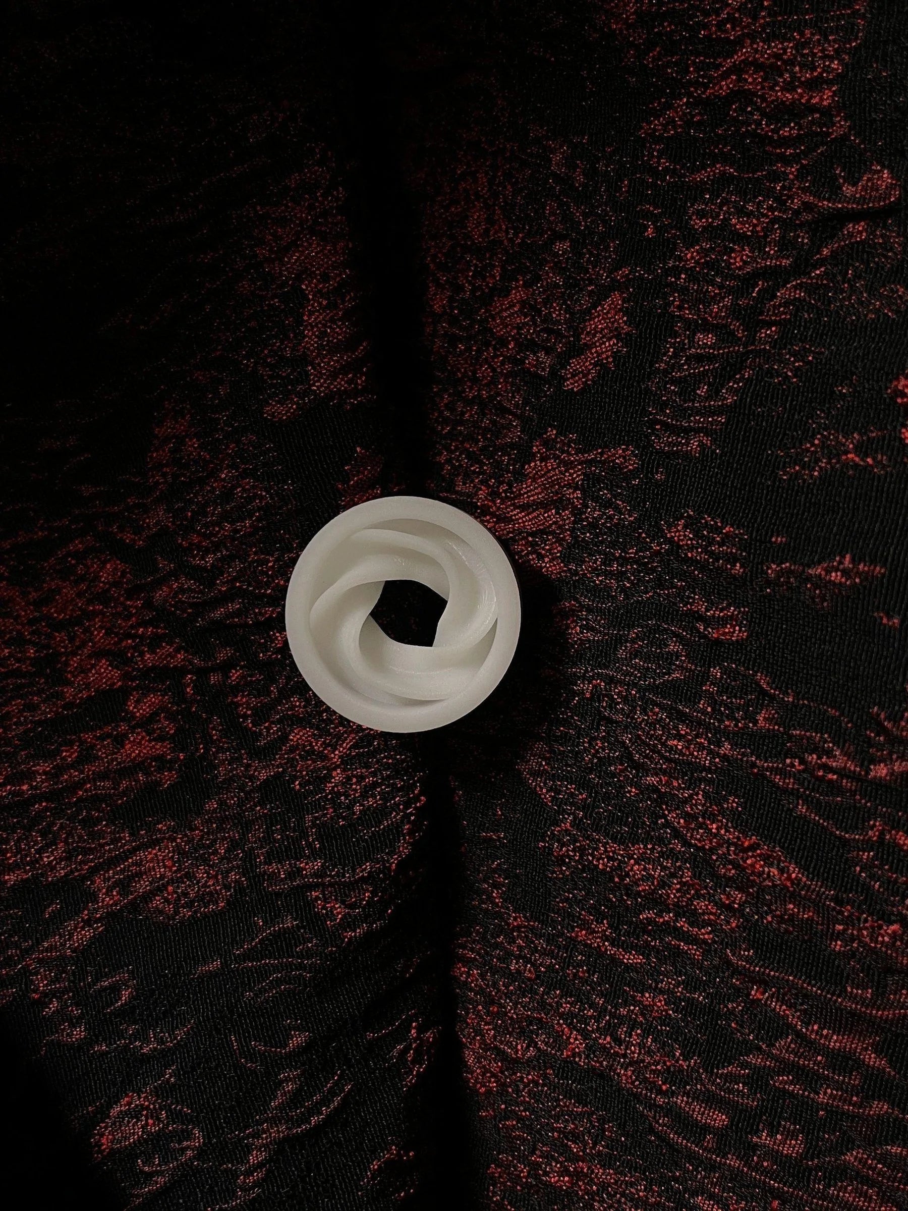 Single white Intertwine double flared ear tunnel on a red and black textured background