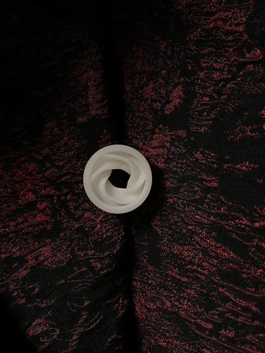 Single white Intertwine double flared ear tunnel on a red and black textured background