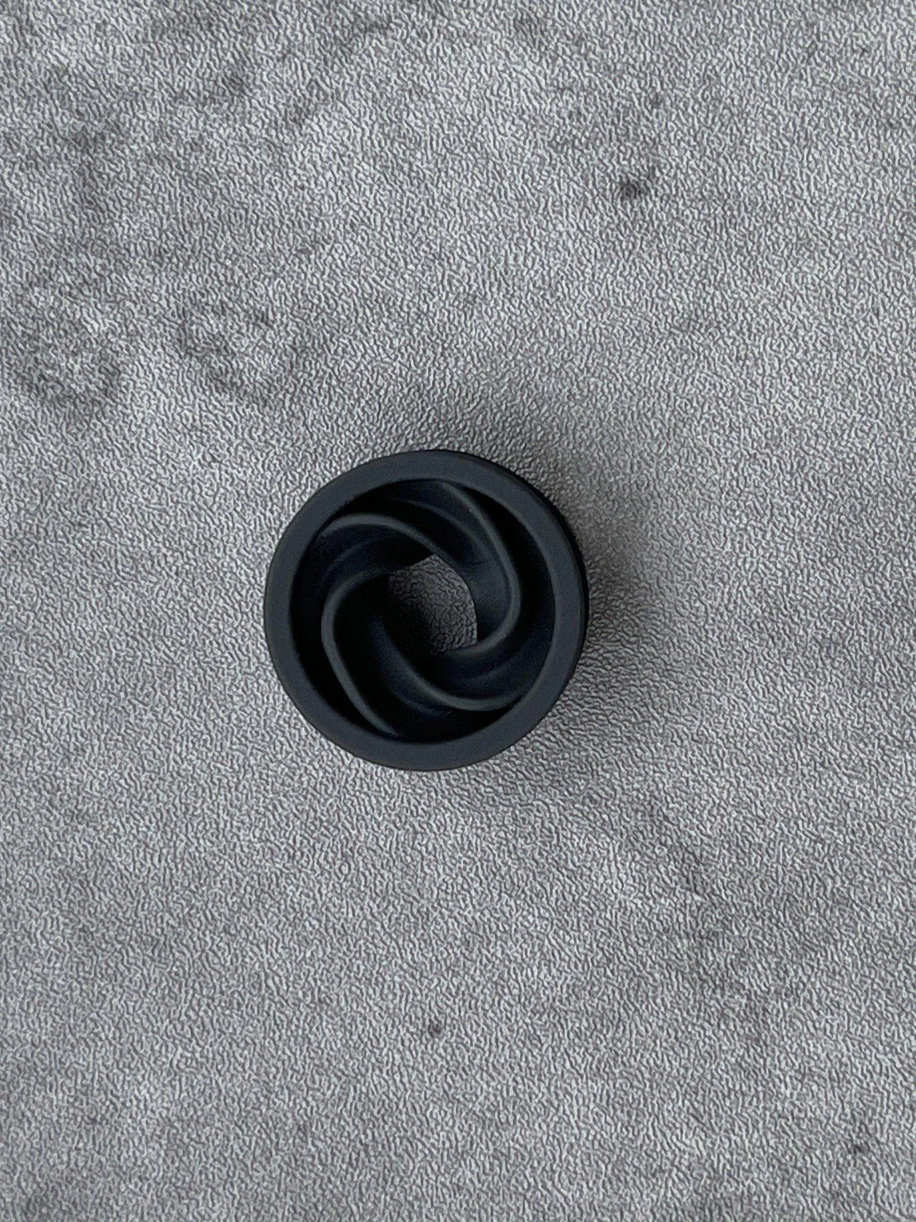 Single black Intertwine double flared ear tunnel on a gray felt background