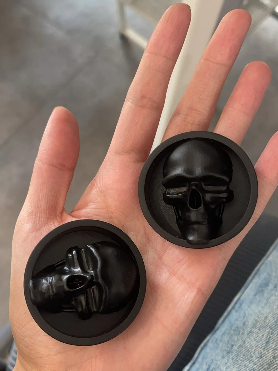 Hand holding a pair of black Dark gaze double flared ear plugs