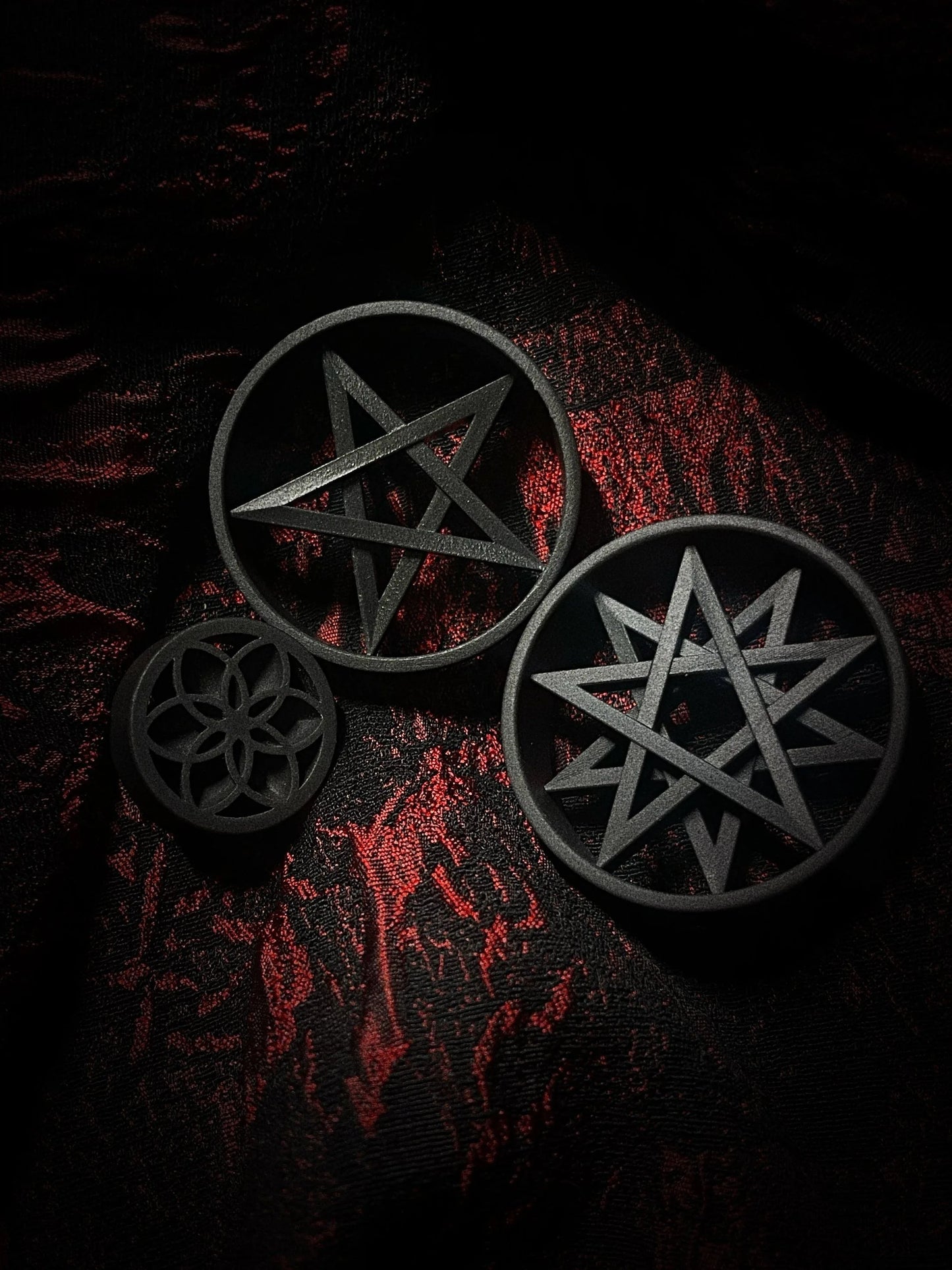 Multiple Decagram double flared ear tunnels in different sizes on a red and black textured background