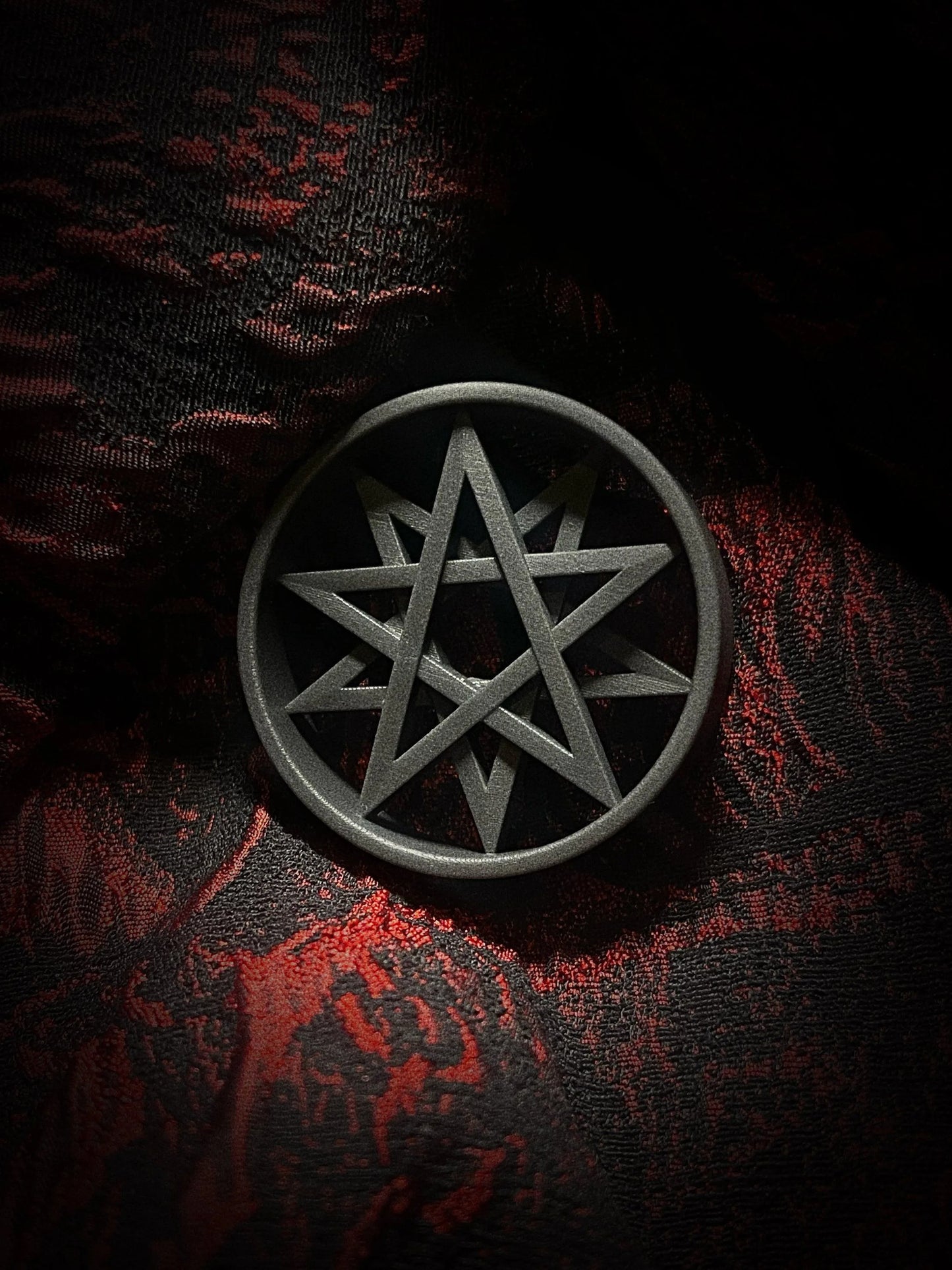 Single Decagram double flared ear tunnel on a red and black textured background