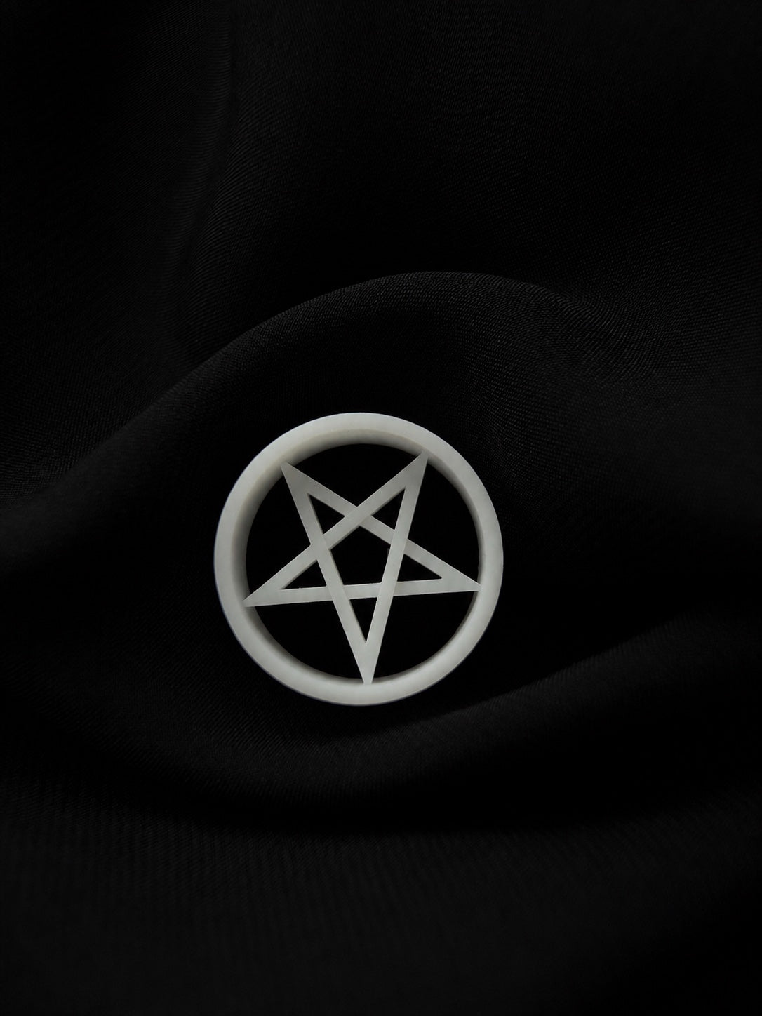 White Pentacle double flared ear tunnel with five-point star cutout on black fabric.